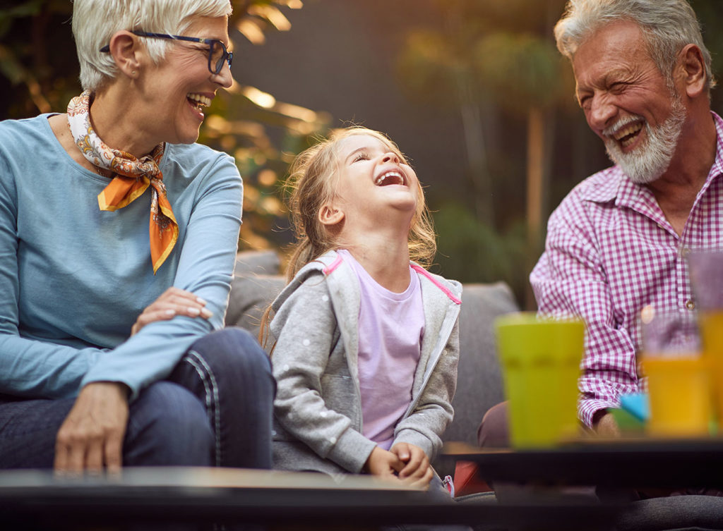 grandparents with granddaughter laughing together